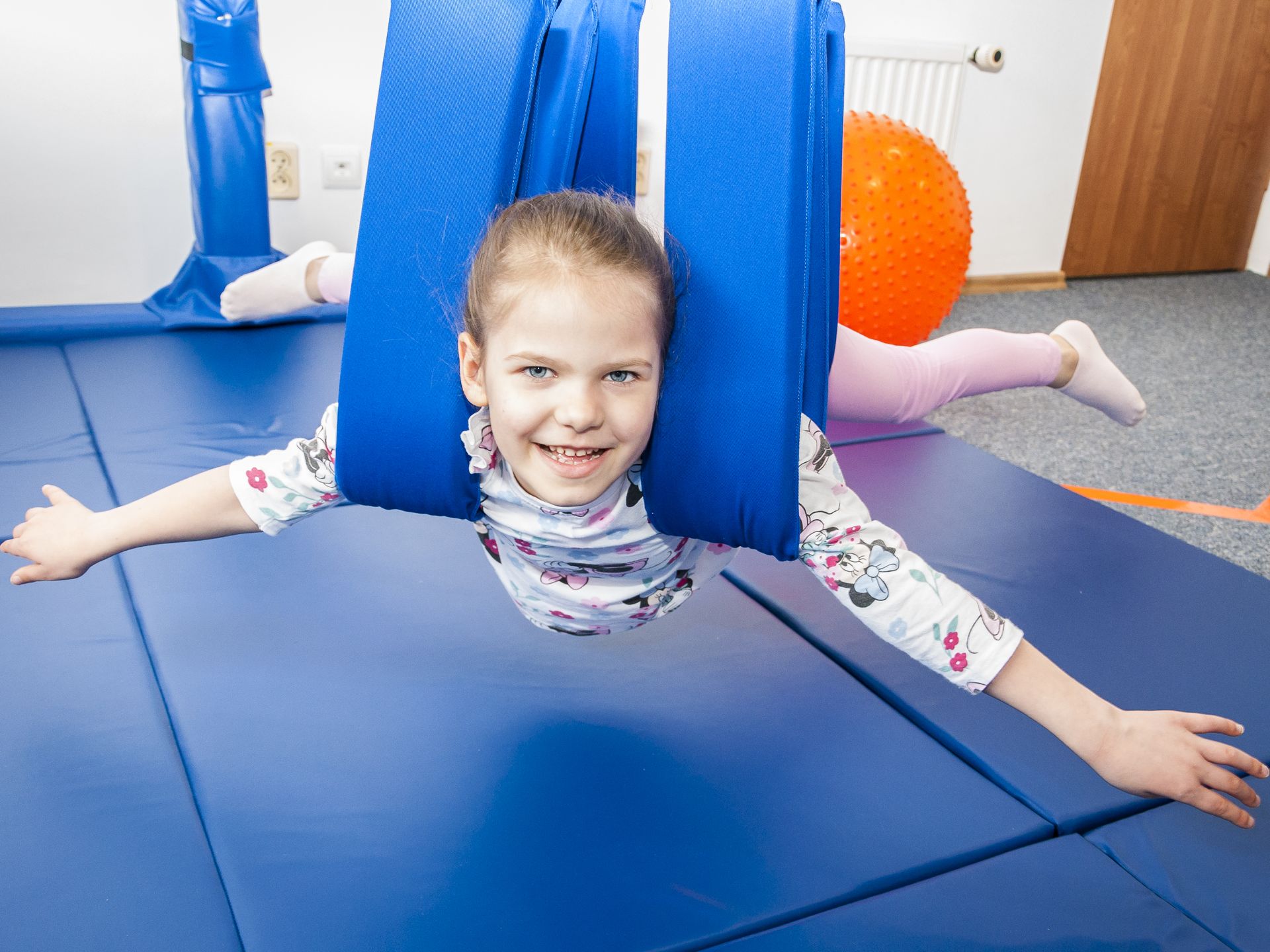 Zajęcia SI: dziewczynka ćwiczy równowagę w systemie podwieszanym „Śmigłowiec” w Centrum Wzlot w Krakowie Trenażer „Śmigłowiec” w gabinecie integracji sensorycznej w Krakowie – rozwój równowagi i pewności siebie poprzez ruch