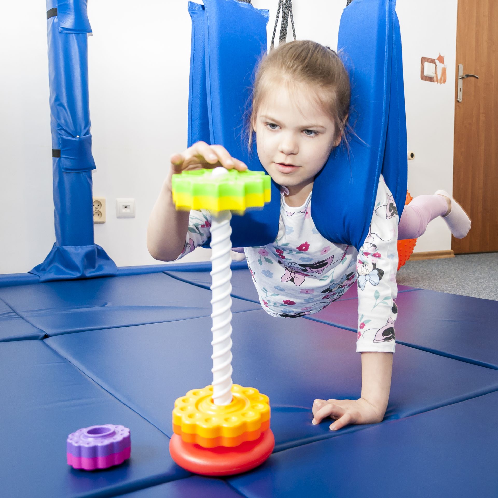 Dziecko w systemie podwieszanym wykonuje zadanie wspierające motorykę i koncentrację w Centrum Wzlot w Krakowie Ćwiczenie SI rozwijające koordynację, siłę i motorykę małą – odkręcanie zębatek z drążka w systemie podwieszanym