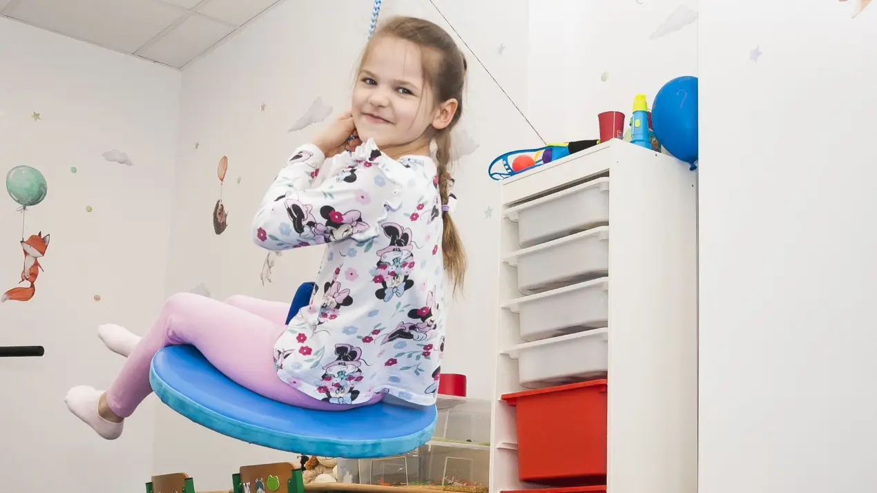Dziewczynka ćwiczy równowagę na huśtawce sensorycznej w Centrum Wzlot w Krakowie