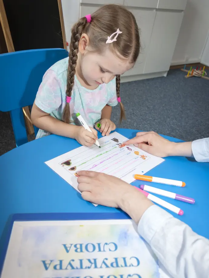 Indywidualne ćwiczenie logopedyczne Zajęcia z logopedą: dziewczynka rysuje linie na karcie